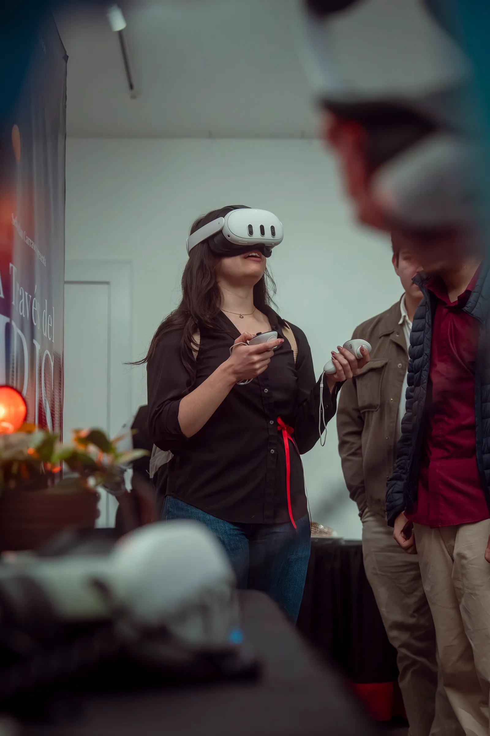 A visitor wearing a VR headset and holding controllers at an A Través del Iris exhibition booth