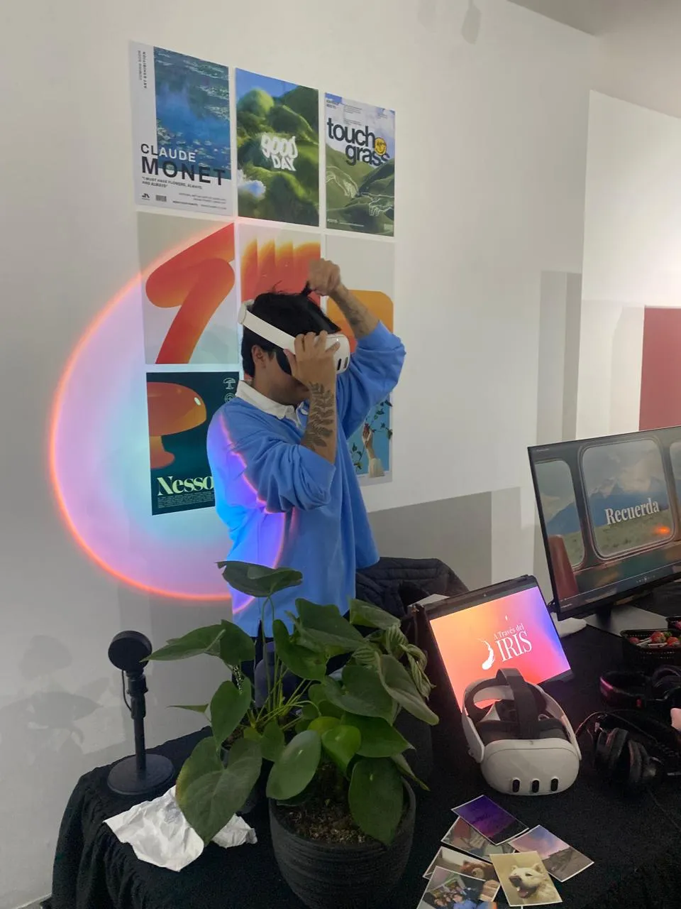 Sebastian wearing a VR headset at an exhibition, with the A Través del Iris title screen showing on a monitor beside him