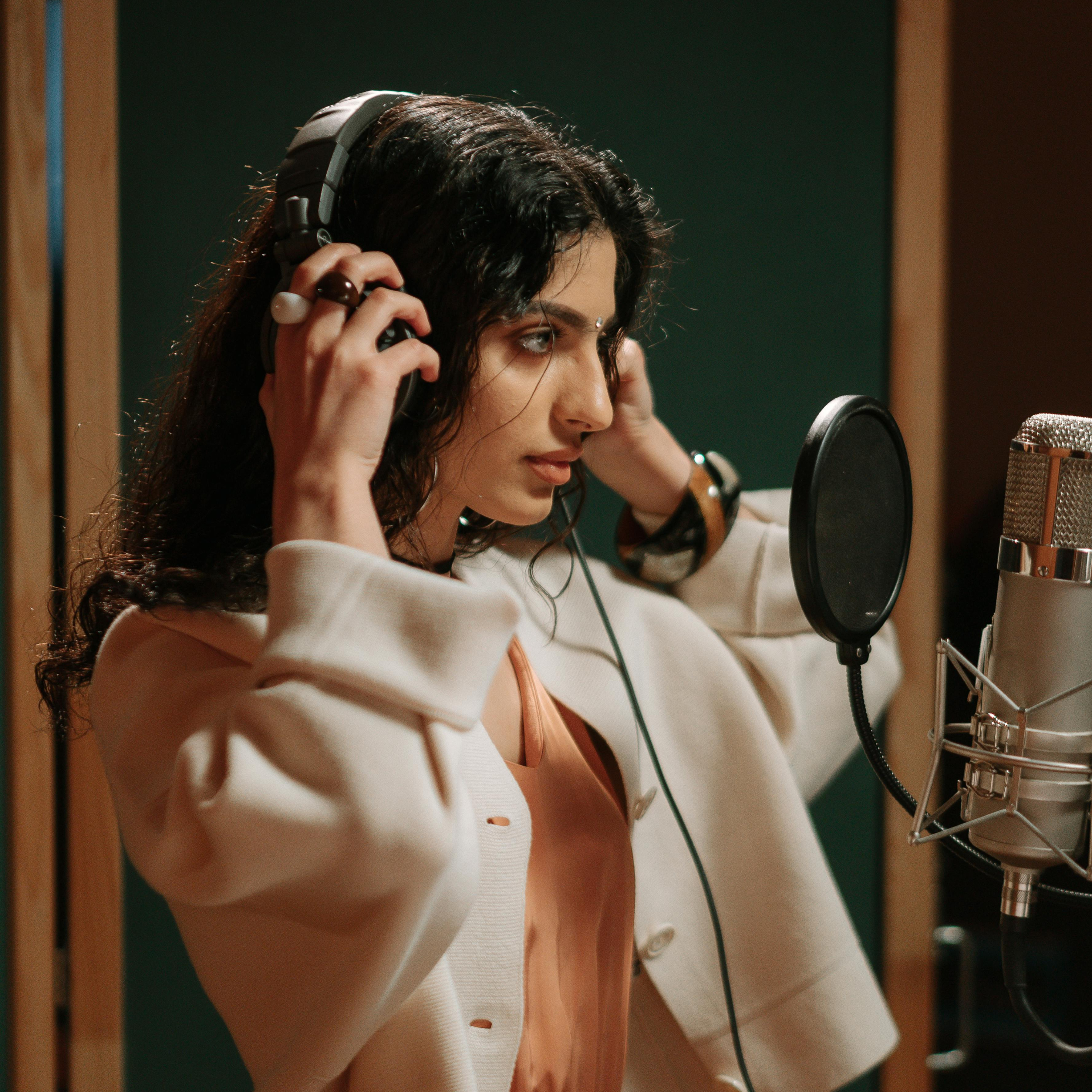 A voice actor adjusting her headphones in a recording booth