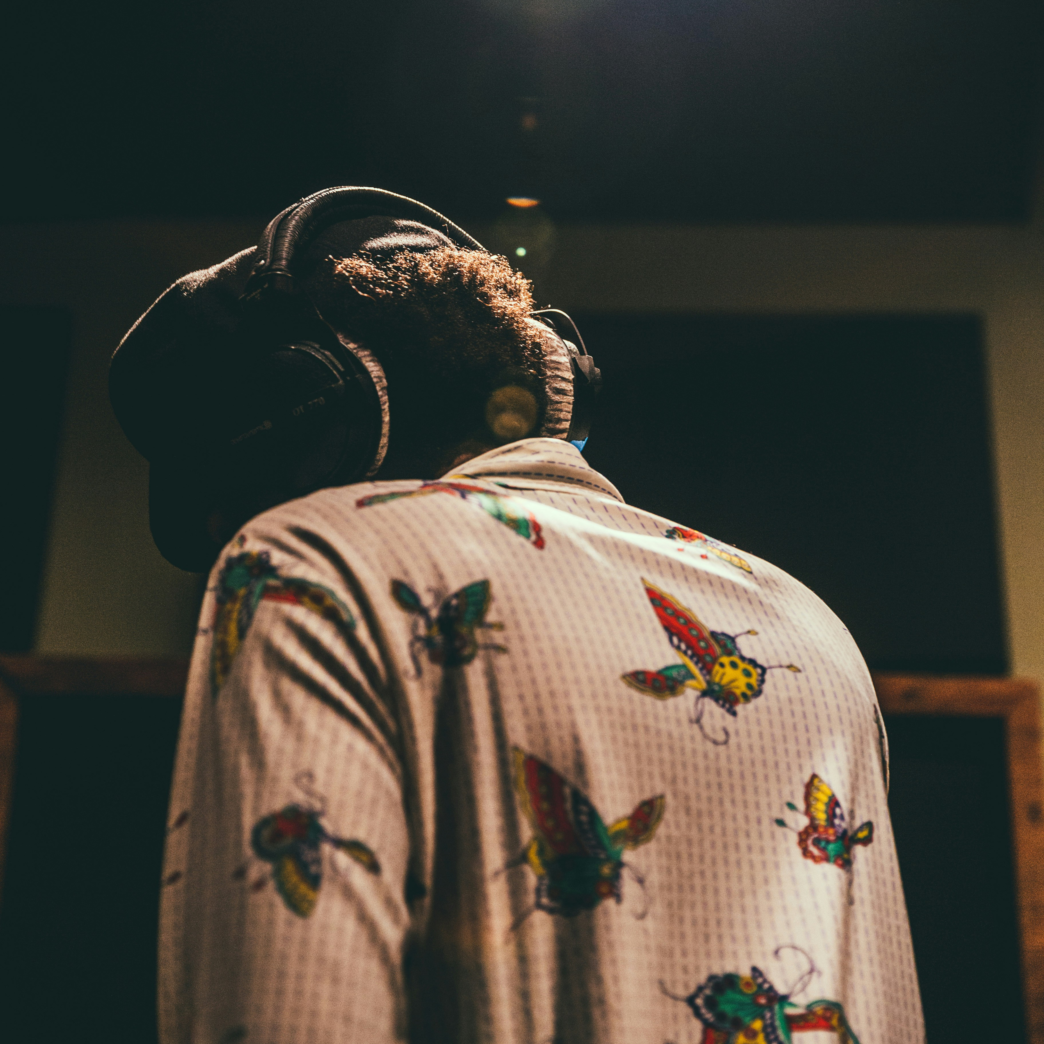 A voice actor listening back to a take, headphones on, in the studio