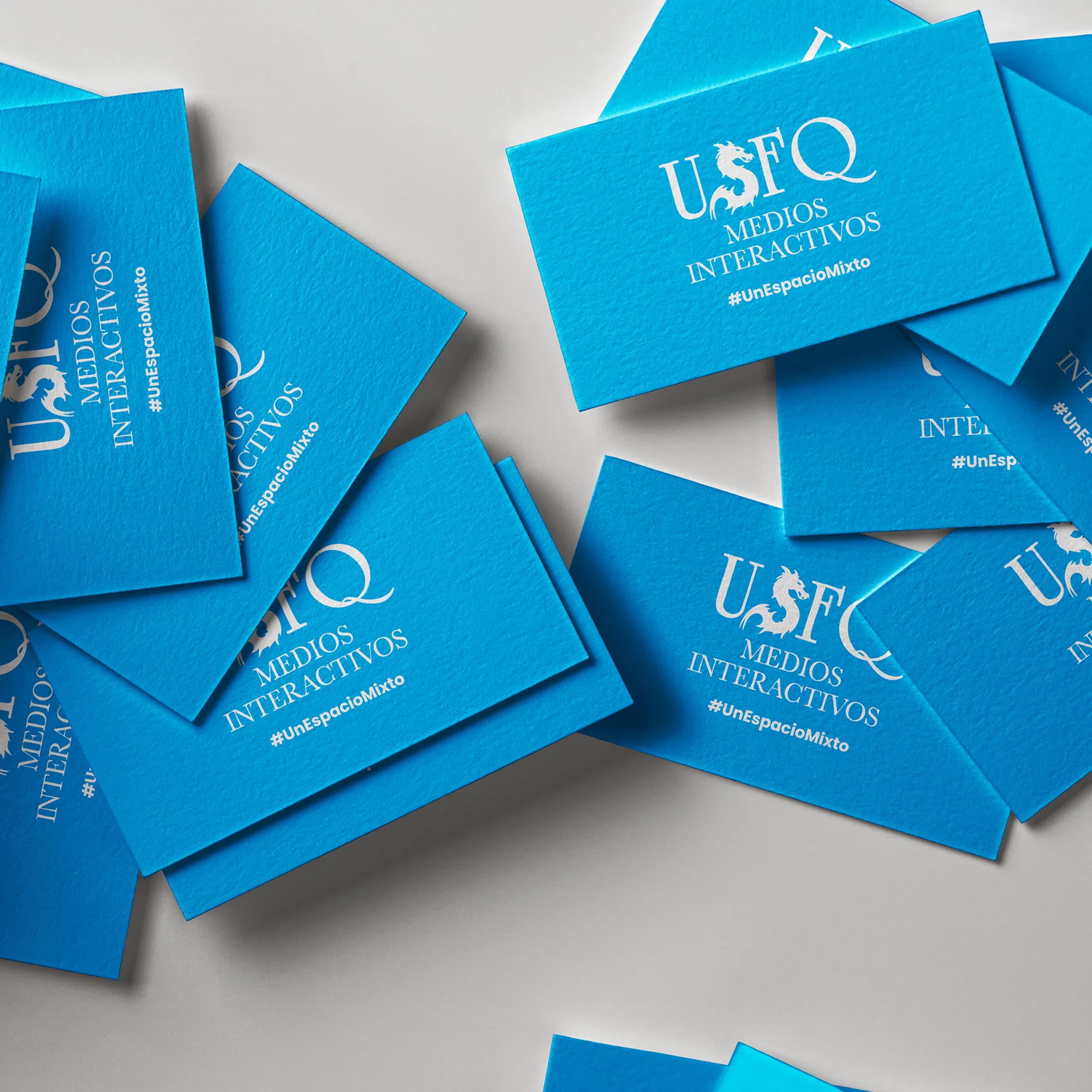 USFQ Medios Interactivos business cards in the program's blue, tagged #UnEspacioMixto