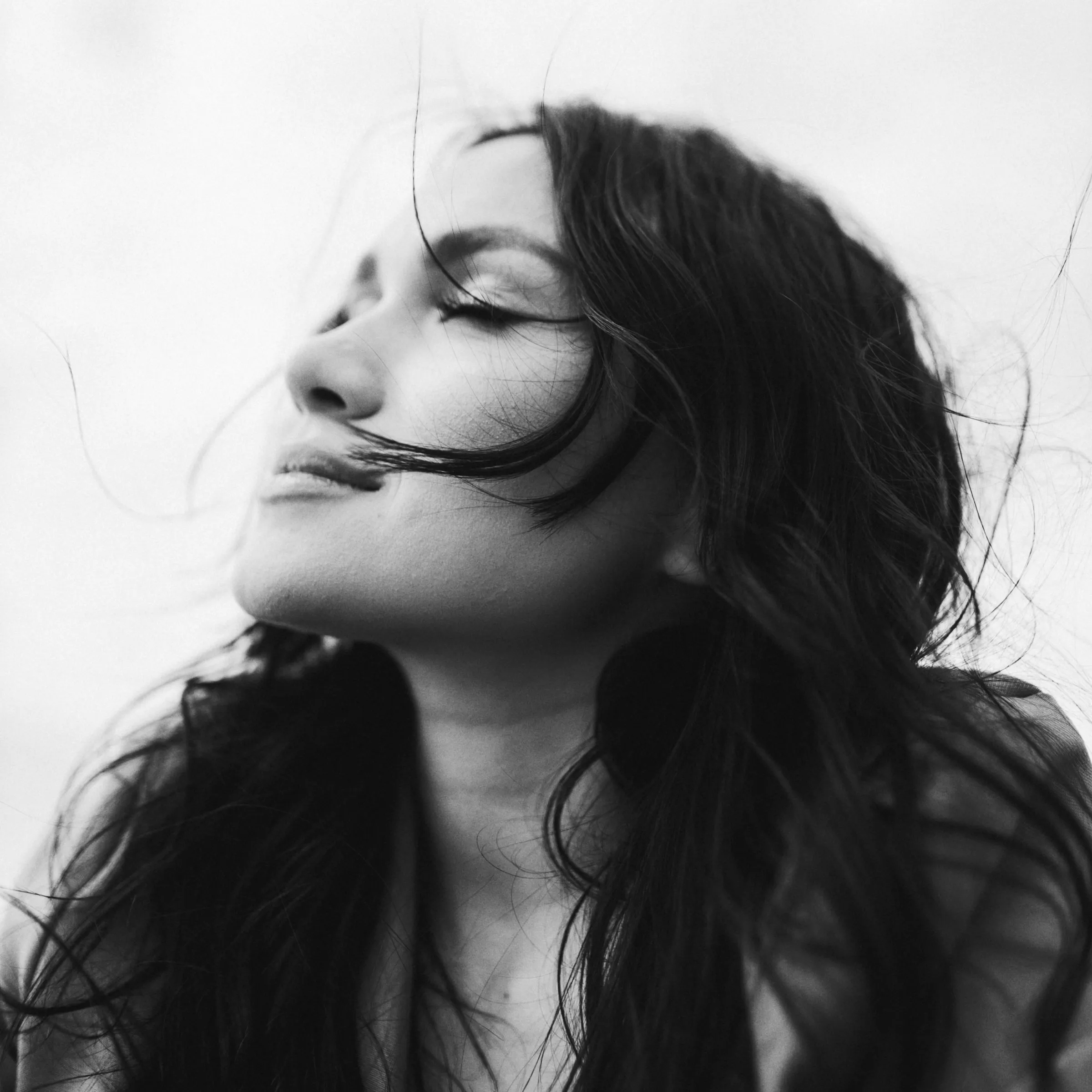 A portrait in black and white, eyes closed, hair in the wind